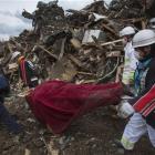 Japanese firemen remove a body from the rubble in the March 11 earthquake and tsunami-destroyed...