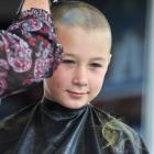 Jessica Power (9) gets her head shaved in Brighton, while supporters watch. Photos by Linda...