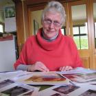 Joan Michelle sifts through some of the information and photos she collected as she wrote her...