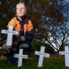Judith Trevathan  places a white cross with the name of her uncle, who died 13 years ago. Photo...