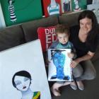 Kate Allan with some of her paintings, while younger son Ben (4) holds one of his artworks. Photo...