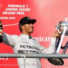 Lewis Hamilton holds up his trophy and a bottle of champagne after winning the US Grand Prix in...