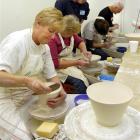 Master ceramicist Victor Greenaway (standing) gives advice to potters (from left) Kathryn Gates...