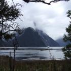 Mitre Peak hides its face behind a veil of cloud as a tourist vessel returns from an excursion on...