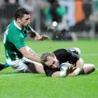 New Zealand halfback Jimmy Cowan scores the first of his two tries in the tackle of Ireland...