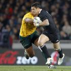 New Zealand's Dan Carter looks to fend off the tackle of Australia's Sekope Kepu during the Tri...