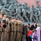 North Korean soldiers salute as civilians bow to bronze statues of North Korea's late founder Kim...