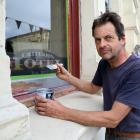 John Baster paints the window frames of the historic Criterion Hotel yesterday, as part of...