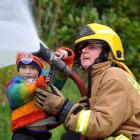 Odin Higbee (3), of Waitati, tries working a fire hose with the help of volunteer firefighter...
