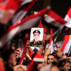 Opponents of Egyptian President Mohamed Mursi hold a poster featuring the head of Egypt's armed...