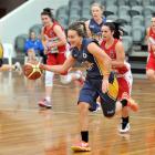 Otago Goldrush player Janet Main makes her way down the court with the ball. She is followed by...