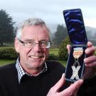 Otago Golf Club general manager Evan Robb holds the St Andrews Cross trophy that has been...
