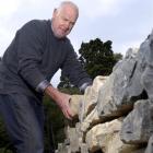 Otago Polytechnic landscape tutor Alan Ferguson adds another rock to a stone wall being built as...