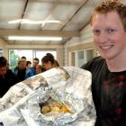 Otago University psychology student John Mighell, of Seattle, unwraps his first hangi at the...