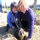 Otama School pupils Laura Whyte (7, left) and Ruby Holz (10) plant a tree on a riparian strip...