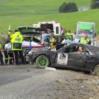 Paramedics (left) treat the driver beside his crashed car where it came to rest after hitting a...
