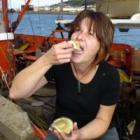 Ariel II crew member Jacinda Fowler eats her first oyster of the season. Photo by Jane Dawber.