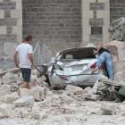 Passersby check a car flattened by masonry from the Christchurch Cathedral after last week's...