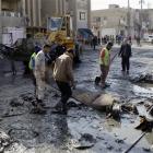 People clean the scene of a car bomb attack in Zafaraniyah, Baghdad, in which 33 people were...
