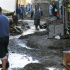 People make their way in a mud-covered street in Monterosso, Italy, after flash flooding hit the...