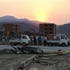 People stand among the rubble in the area devastated by the Match 11 earthquake and tsunami in...