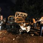 People stand near a police car that was destroyed in an explosion in front of a police station in...