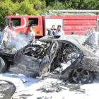 People stand near debris and a damaged vehicle at the scene of a car bomb attack in the al-Mezze...