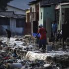 People sweep the garbage that was brought down by heavy rains overnight in the Cite Soleil...