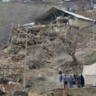 People walk in the debris of houses destroyed in an earthquake, in Okcular village in the eastern...