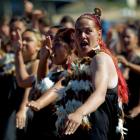 Women and men perform a haka on the beach.