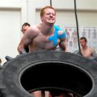 Personal trainer Ben Thompson pushes through the pain flipping a tyre at a CrossFit competition...