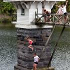 Teenagers leap from the bridge to the valve tower at Ross Creek Reservoir in Dunedin yesterday....