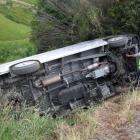 Police Constable Darren Cox, of Balclutha, surveys a damaged vehicle that rolled down a steep...