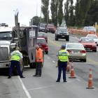 Police inspect a commercial truck after it rolled into a retaining wall beside the south-bound...