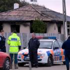 Police stand outside the burnt house yesterday.