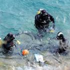 Police divers recover a number plate from Lake Wakatipu after examining the rental car that...