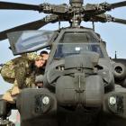 Prince Harry climbs up to examine the cockpit of an Apache helicopter at Camp Bastion in...