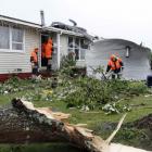 Rescue workers search amid the devastation in the suburb of Hobsonville after a tornado went...