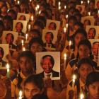 Schoolchildren hold candles and portraits of Nelson Mandela during a prayer ceremony at a school...