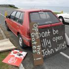 Signs arguing for the reopening of John Wilson Ocean Dr, lean against a car parked at the...