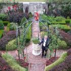 Sir Miles stands by an old font in the centre of the formal Red Garden. The use of red was echoed...