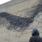 South African-based street artist DALeast waits for a break in the rain to continue his work in...