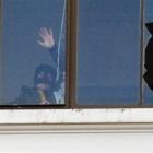 A man on the top floor of Dunedin's former chief post office building holds a marine flare to his...