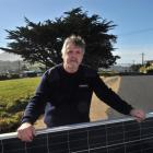 Stu Nicholson holds a solar panel set  to be installed on the roof of his Brighton home, which is...
