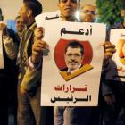 Supporters of Egypt's president Mohamed Mursi hold banners reading 'I support the President's...