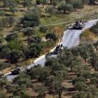 Syrian tanks, seen from the Turkish village of Saribuk, drive towards the town of Darkush in...