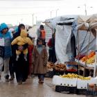 Syrians refugees walk near street vendors after heavy rain, at the Al-Zaatari refugee camp in the...