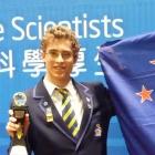 Taieri College pupil Ben Mulholland poses proudly next to the New Zealand flag after he won the...