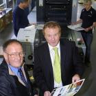 Taieri Print owner Peter Moore (left)  and  chief executive Ken Blair check a page from the new...