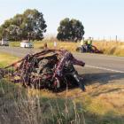 The front of a Mazda Familia car sits beside  State Highway 1 after it broke away from the rest...